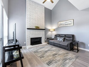 A living room with a fireplace, a sofa, a coffee table, and a TV.