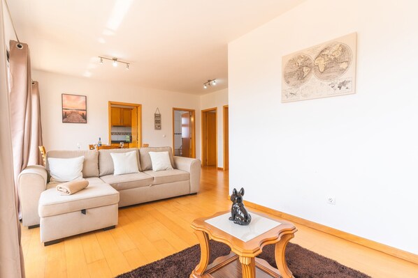 A living room with a sofa, a small table, and a painting on the wall. - Porlamar III by Atlantic Holiday (Calheta)