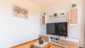 Uma sala de estar moderna com televisão de tela plana, armários de madeira, uma mesa pequena e uma obra de arte com um mapa-múndi.