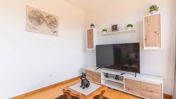 A modern living room with a flat-screen TV, wooden cabinets, a small table, and a world map artwork.