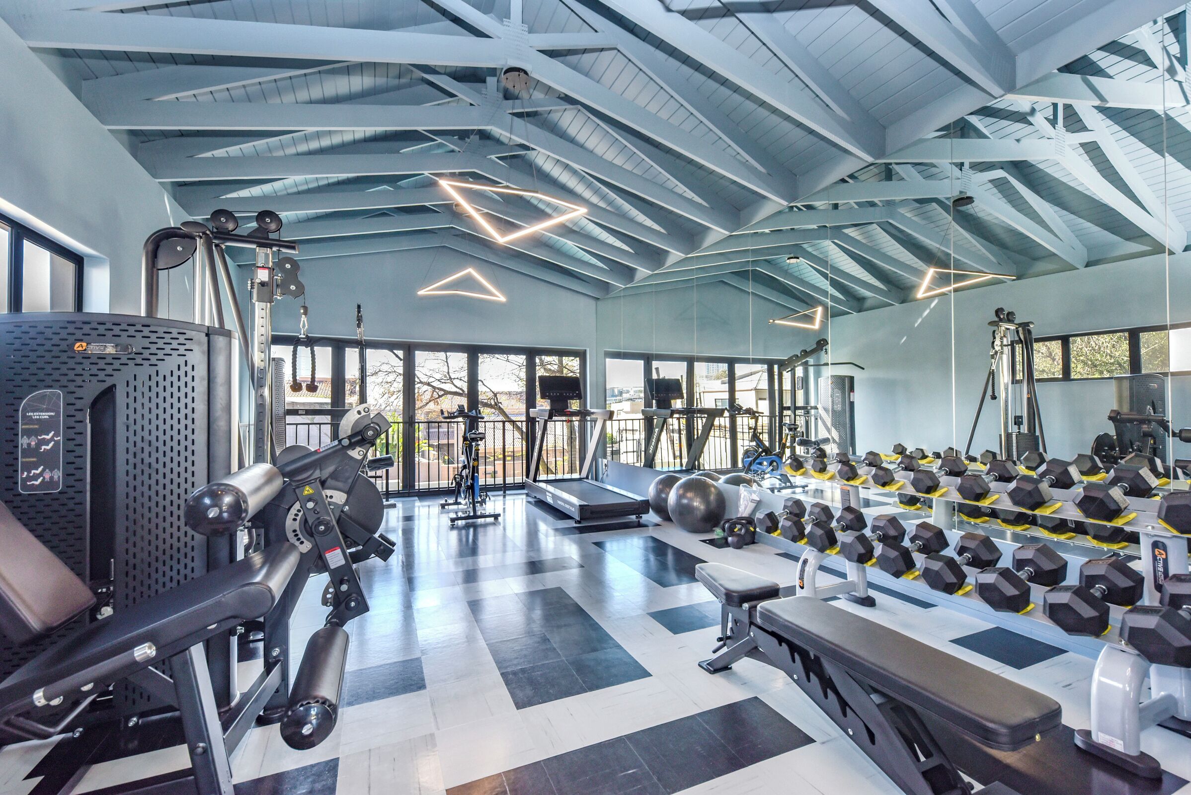 A gym with exercise equipment, a treadmill, and dumbbells.
