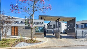 Een modern gebouw met een bord waarop 'TUNTEN' staat en een overdekte ingang.