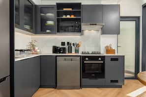 A modern kitchen with a dishwasher, oven, and built-in appliances. - The Valour | Designer Escape and Private Balcony (Cape Town)