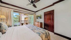 A bedroom with a bed, a ceiling fan, a wooden door, and a view of the outside balcony. - New Listing- Waipouli Ocean front, Pool, AC, GYM, Waterslide! (Kapaa)