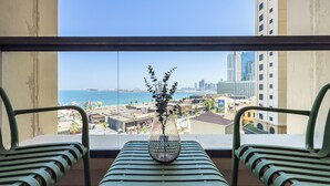 A balcony with a view of the sea and cityscape, a green bench, and a vase with plants. - Upgraded Modern 3BR+Kids | JBR | Sea and Ain View (Dubai)