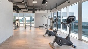 A gym with cardio equipment, a bench, and large windows. - Upgraded Modern 3BR+Kids | JBR | Sea and Ain View (Dubai)