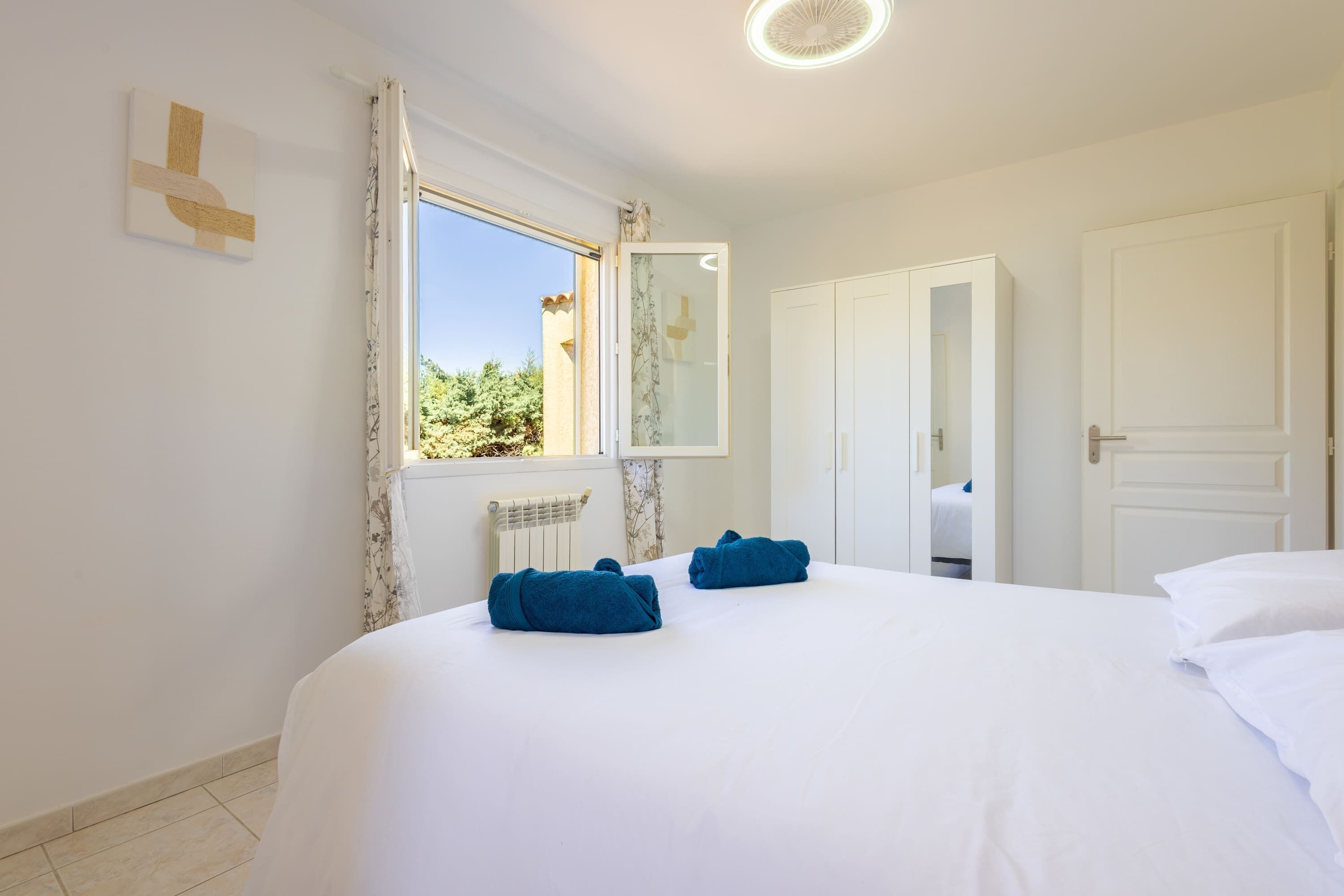 A hotel room with a bed, a window with curtains, a radiator, and a wardrobe.