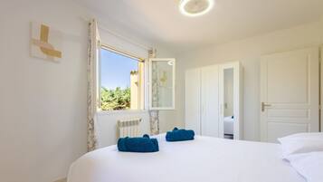 A hotel room with a bed, a window with curtains, a radiator, and a wardrobe.