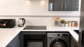 A compact kitchen with a built-in oven, microwave, and washing machine.