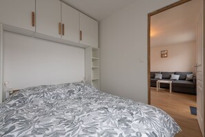 A bedroom with a bed, a wardrobe, and a sofa in the adjacent living area. - La Bergerie de Cayeux - à 350 m de la plage (Cayeux-sur-Mer)