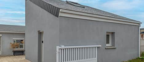 Un bâtiment d’un seul étage, à l’extérieur gris, avec une petite fenêtre et une clôture blanche.