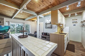 A modern kitchen with wooden cabinets, a built-in microwave, and a small island with a sink. - Quiet Tahoe Retreat • Near Heavenly & Hiking (Stateline)