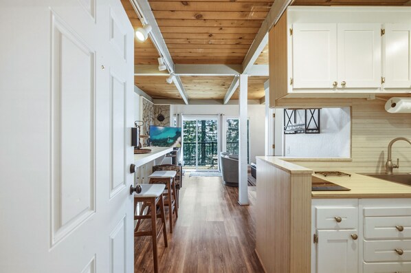 Eine moderne Küche mit Holzbalken, weißen Schränken und Blick ins Freie.