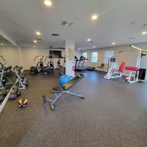 Een sportschool met diverse fitnessapparaten, waaronder loopbanden, krachttoestellen en gewichten.