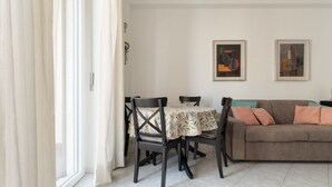 A dining area with a table and chairs, a sofa, and two framed artworks on the wall. - A comfortable and welcoming 55-square-meter apartment, ideal for four people, located on the sixth floor of a building with an elevator.The property is situated in the Sondrio district—a lively, modern, and highly convenient area centered around the M3 (Milan)