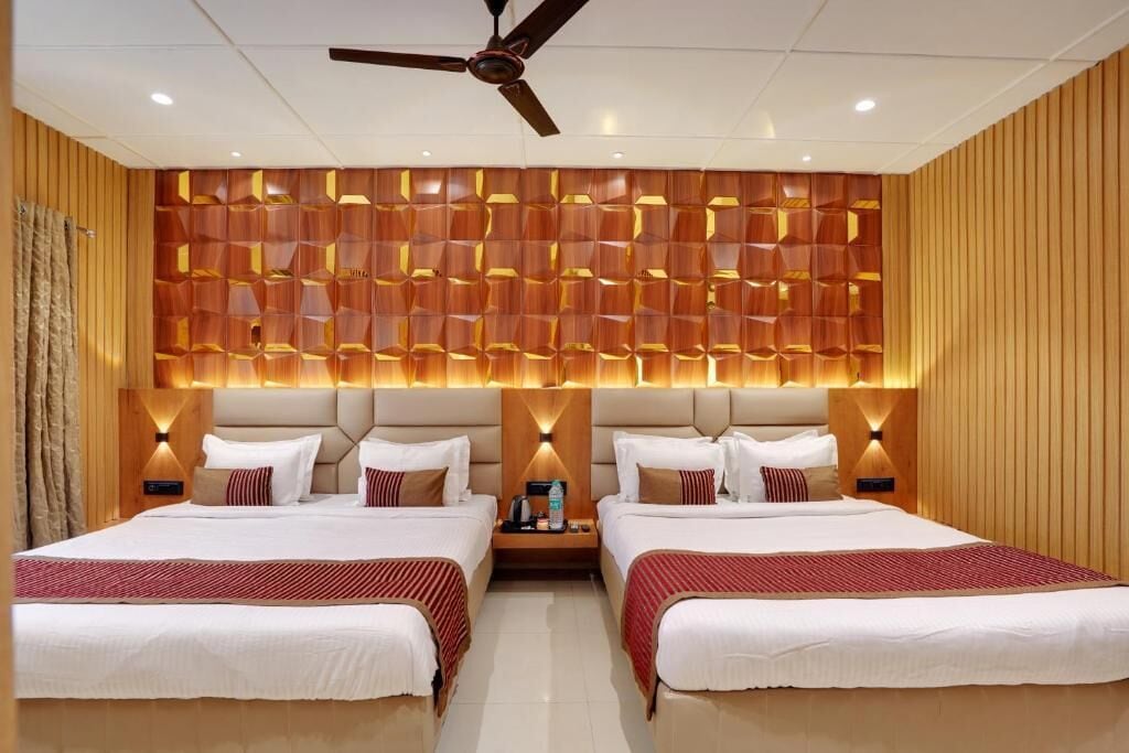 A hotel room with two beds, a ceiling fan, and a wall with a geometric pattern.