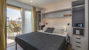 A modern bedroom with a bed, bedside tables, a built-in wardrobe, and a view of the outdoors. - hu Eraclea Mare (Eraclea Mare)