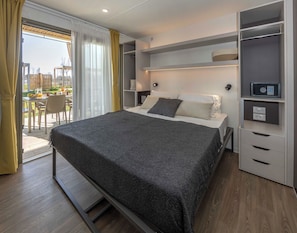A modern bedroom with a bed, bedside tables, a built-in wardrobe, and a view of the outdoors. - hu Eraclea Mare (Eraclea Mare)