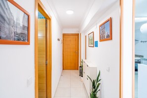 A hallway with wooden doors, framed pictures on the walls, and a tiled floor. - Cubo's Manuel Apartment & Pool / communal pool / terrace / free wifi (Benalmádena)
