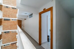 A narrow balcony with a white railing, a door with a wooden frame, and a trash bin. - Cubo's Manuel Apartment & Pool / communal pool / terrace / free wifi (Benalmádena)
