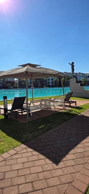 A poolside area with a gazebo, lounge chairs, and a statue. - The Blyde Noak South Africa (Pretoria)