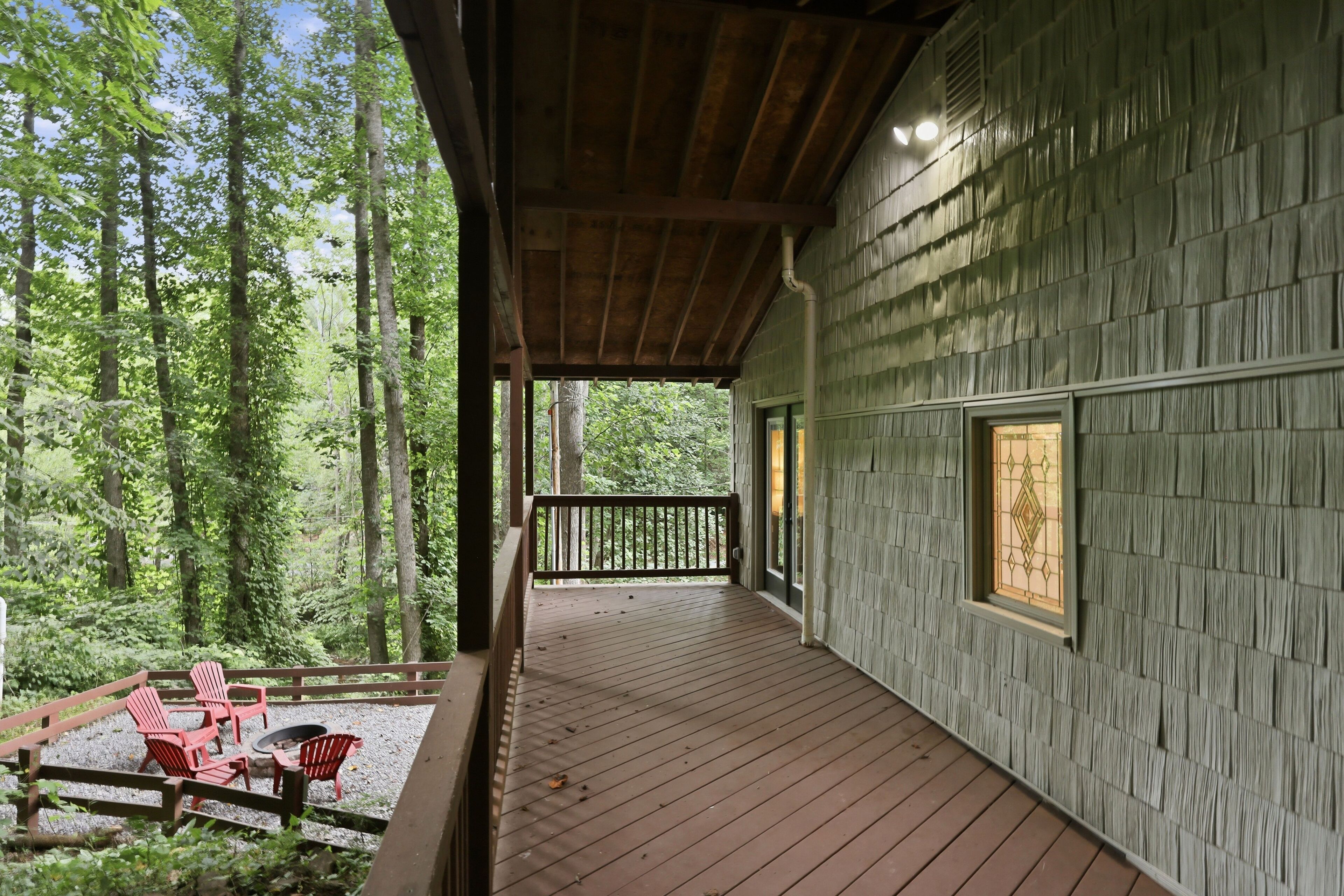 A wooden deck with a railing, surrounded by a forest.