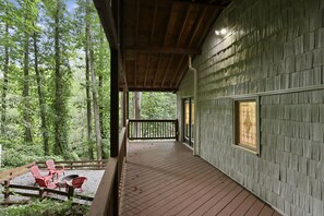 Una terraza de madera con barandilla, rodeada de un bosque.