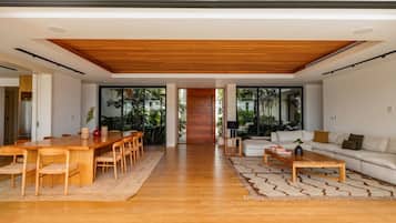 A spacious living area with a wooden dining table and chairs, a sofa, and a coffee table.