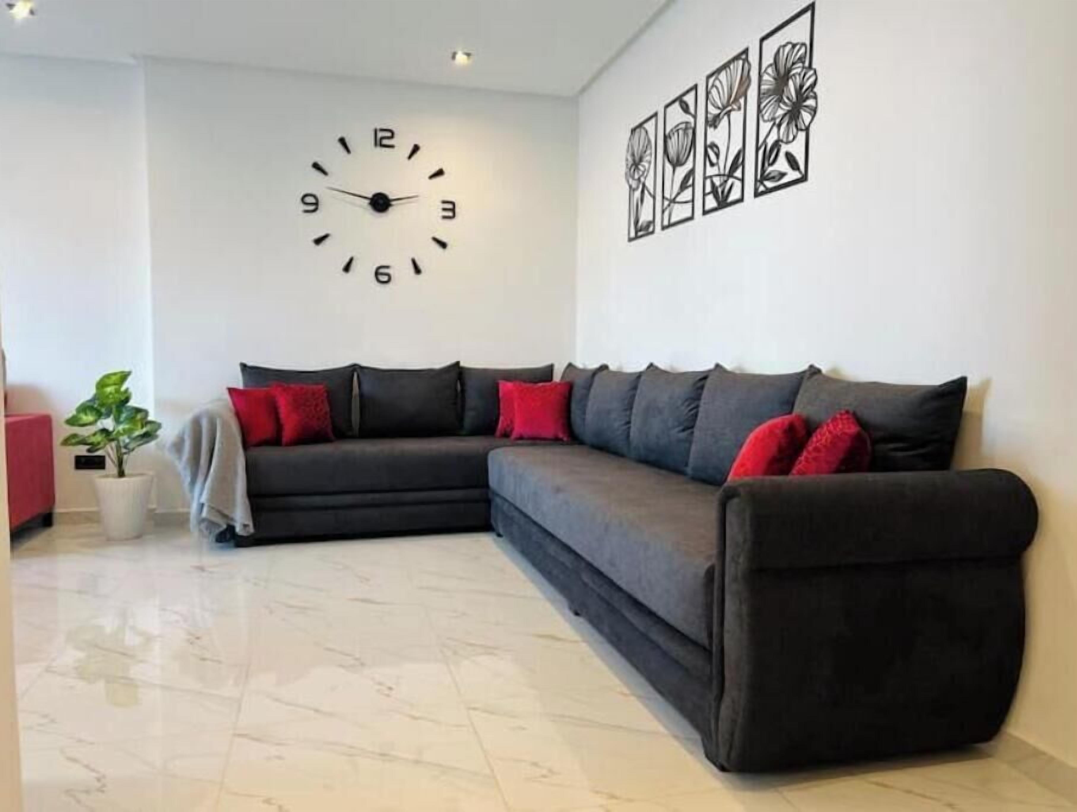 A living room with a sectional sofa, a wall clock, and framed artwork.
