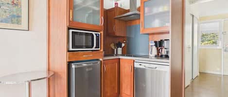 Una cocina compacta con electrodomésticos integrados, una pequeña mesa redonda y armarios de madera.