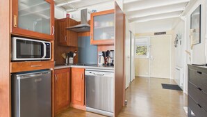A compact kitchen with wooden cabinets, a microwave, a dishwasher, and a coffee maker. - Sea View Balcony & Pool - Apartment for 2 (Le Croisic)