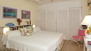 Ein Schlafzimmer mit Bett, Sessel, Schreibtisch und Kleiderschrank.