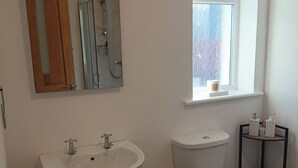 Een badkamer met een witte wastafel, toilet en een raam boven het toilet.