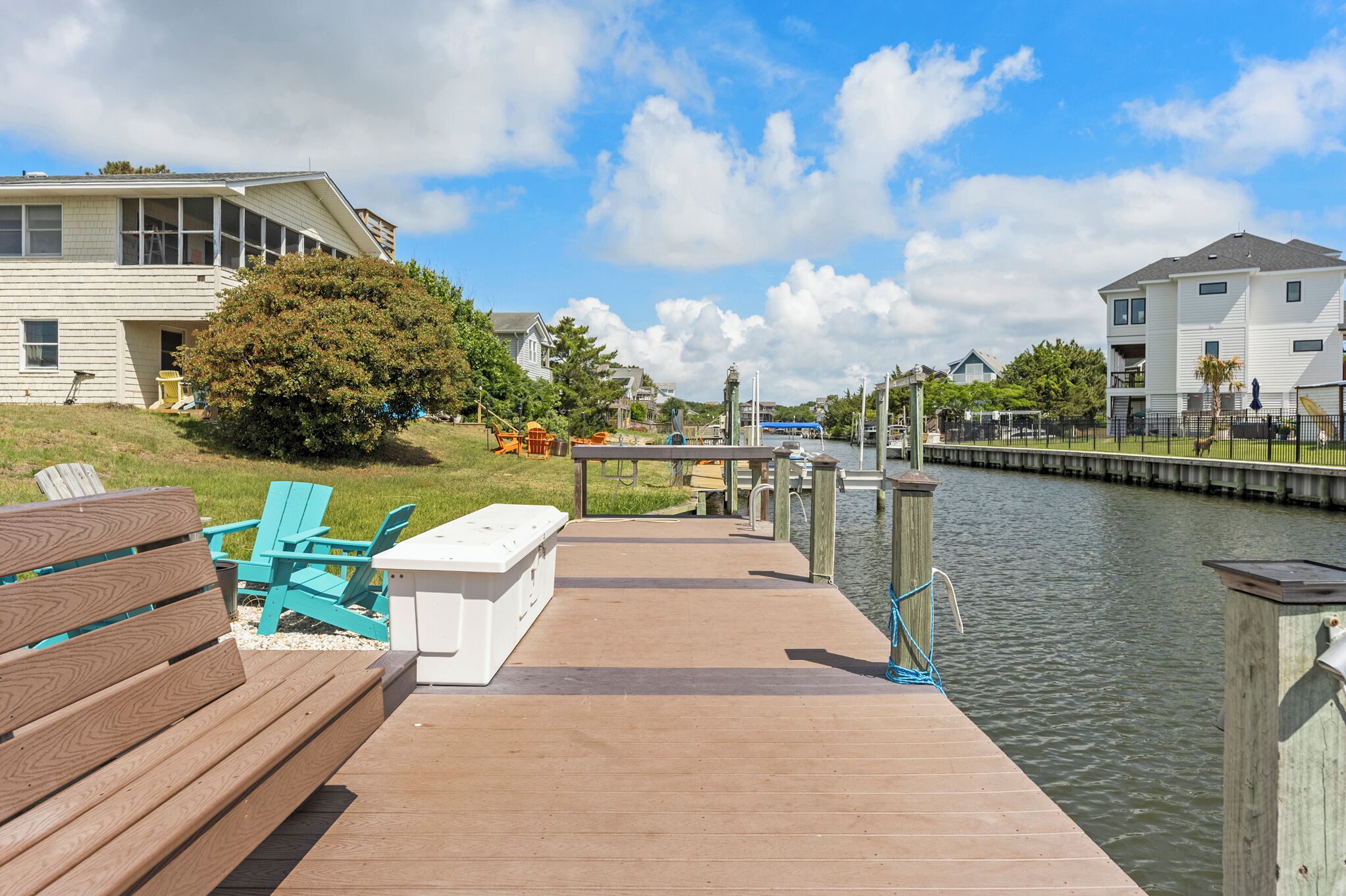 A wooden dock leading to a calm water body with a clear sky.