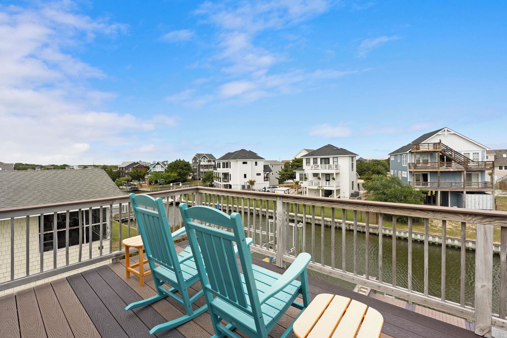 A deck with two chairs and a table overlooking a body of water with buildings in the background.
