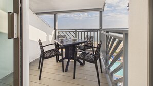 Et overdækket udendørs område med et bord og stole, en pool i baggrunden og udsigt til himlen.