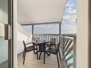 A covered outdoor area with a table and chairs, a pool in the background, and a view of the sky. - Apartment for 2 with Sea View & Pool (Le Croisic)