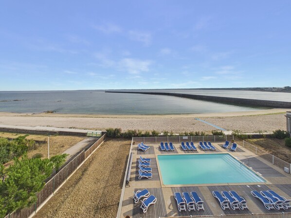 A pool area with lounge chairs and a view of the beach. - Apartment for 2 with Sea View & Pool (Le Croisic)