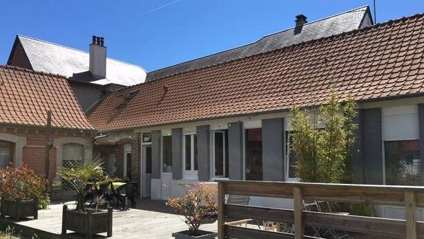 A residential building with a tiled roof, a wooden deck, and potted plants. - Vacation Rental in the Somme Bay Area for 6 People (Fort-Mahon-Plage)