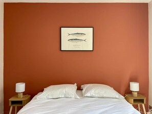 Ein Hotelzimmer mit einem Bett, zwei Nachttischlampen und einem gerahmten Bild einer Fische an der Wand.