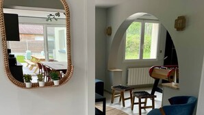 A modern living room with a round mirror, a wooden side table, a blue chair, and a foosball table. - The Spot in the Baie de Somme (Quend)