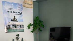 A living room with a sofa, a TV, a plant, and a poster on the wall. - The Spot in the Baie de Somme (Quend)