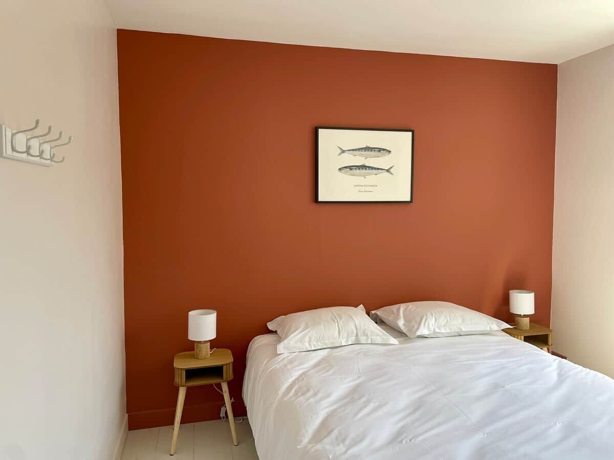 A bedroom with a single bed, two bedside tables with lamps, and a framed fish illustration on the wall.