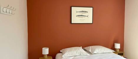 A bedroom with a single bed, two bedside tables with lamps, and a framed fish illustration on the wall.