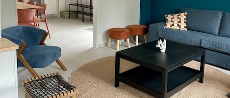 A modern living room with a blue accent wall, a flat-screen TV, a coffee table, and seating arrangements including a sofa and chairs.