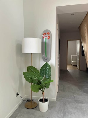 A hallway with a potted plant, a floor lamp, and a wall-mounted thermometer. - La Menuiserie Vacation Rental in the Somme Bay—Accommodates 15 People (Fort-Mahon-Plage)