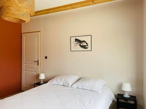 Ein Schlafzimmer mit einem Bett, zwei Nachttischen mit Lampen, einer Tür und einem Wandbild.
