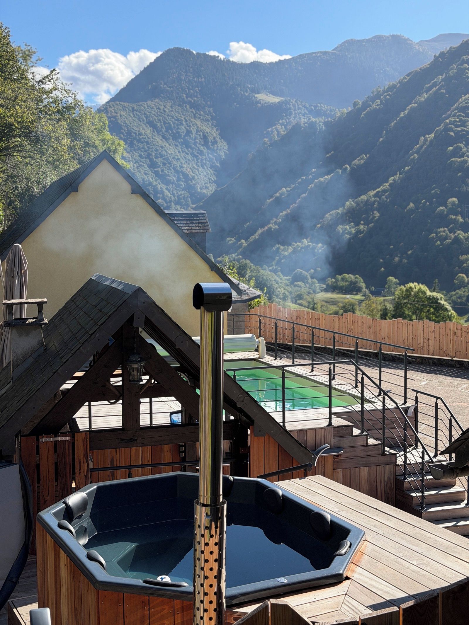 Banheira de hidromassagem em deck de madeira com montanhas ao fundo.