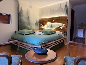 A bedroom with a bed, a round table with a teapot, and a dresser.