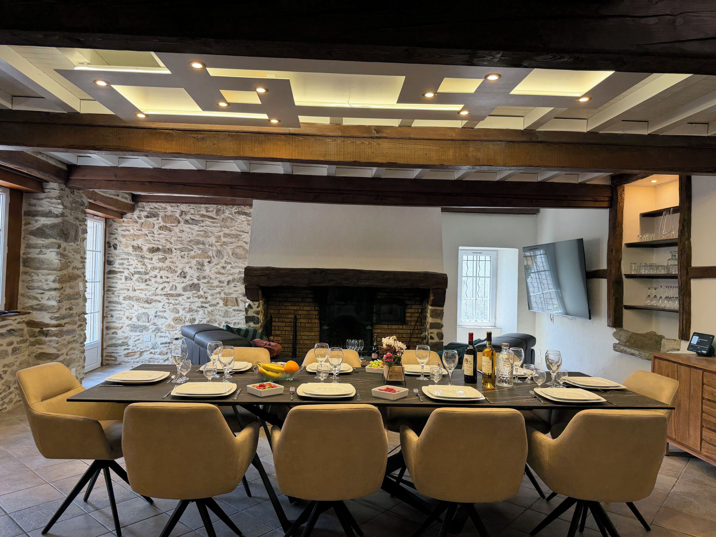 Uma sala de jantar com parede de pedra, lareira e design moderno no teto.